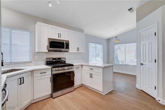 1005 Transom Dr, Las Vegas, NV 89128 - kitchen featuring stainless steel appliances, light wood-style floors, a peninsula, white cabinetry, and lofted ceiling