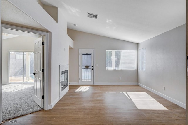 1005 Transom Dr, Las Vegas, NV 89128 - unfurnished living room featuring vaulted ceiling, plenty of natural light, wood finished floors, and a glass covered fireplace