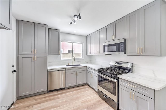 516 Donner St, Las Vegas, NV 89107 - kitchen with stainless steel appliances, gray cabinetry, light wood-type flooring, and light stone counters