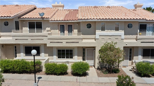 2219 Rugged Mesa Dr, Laughlin, NV 89029 - view of front of house with a balcony, stucco siding, a tile roof, and a chimney