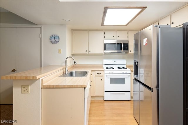 3740 Desert Marina Dr Unit 7, Laughlin, NV 89029 - kitchen featuring stainless steel appliances, a peninsula, light countertops, light wood-style floors, and white cabinetry