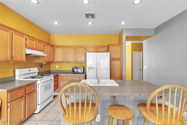 9605 Rainfall Ave, Las Vegas, NV 89147 - kitchen featuring white appliances, under cabinet range hood, a breakfast bar, light tile patterned floors, and recessed lighting