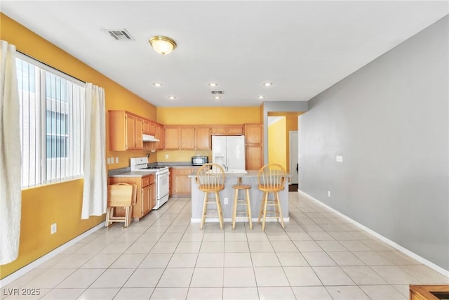 9605 Rainfall Ave, Las Vegas, NV 89147 - kitchen with white appliances, under cabinet range hood, light countertops, a breakfast bar area, and a center island