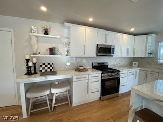 2712 Rialto Rd, Las Vegas, NV 89108 - kitchen featuring stainless steel appliances, white cabinetry, tasteful backsplash, open shelves, and light wood finished floors