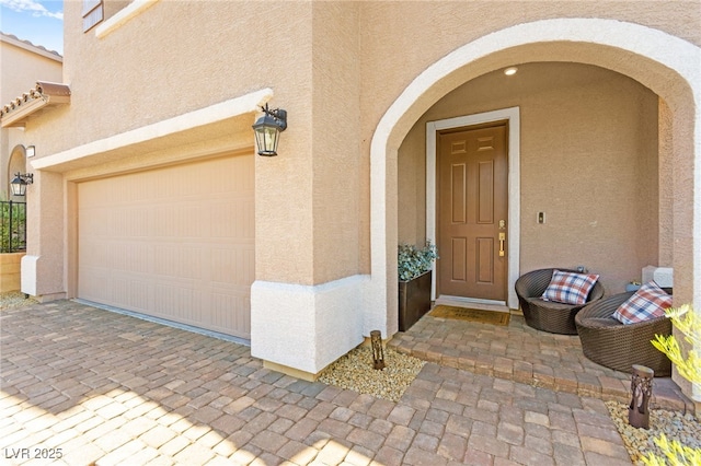 10940 Oregano Ave, Las Vegas, NV 89166 - doorway to property featuring stucco siding, decorative driveway, and an attached garage