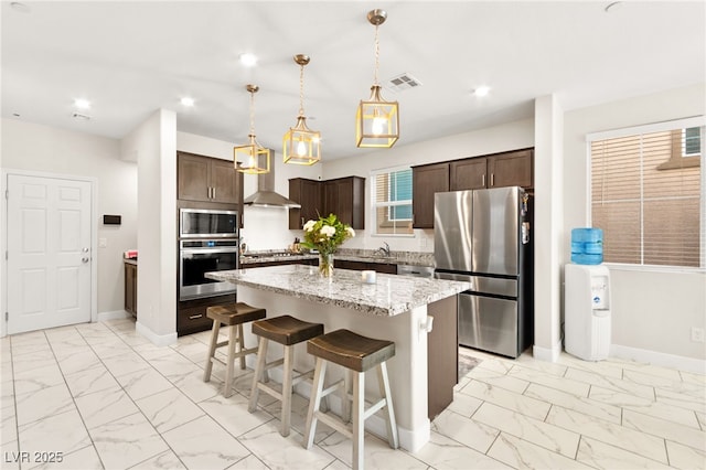 10940 Oregano Ave, Las Vegas, NV 89166 - kitchen featuring appliances with stainless steel finishes, light marble finish flooring, dark brown cabinets, a kitchen island, and recessed lighting