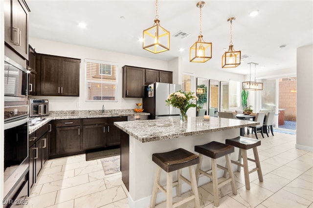 10940 Oregano Ave, Las Vegas, NV 89166 - kitchen featuring stainless steel appliances, light marble finish floors, plenty of natural light, a breakfast bar, and recessed lighting