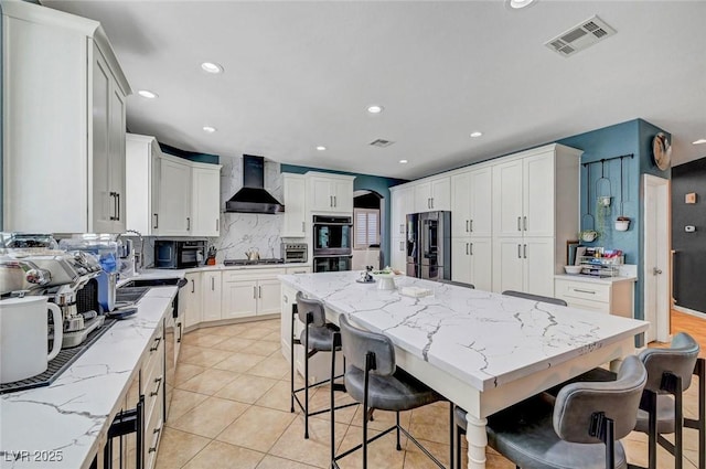 11417 Rock Cove Way, Las Vegas, NV 89141 - kitchen featuring wall chimney exhaust hood, appliances with stainless steel finishes, a kitchen island, tasteful backsplash, and light stone countertops