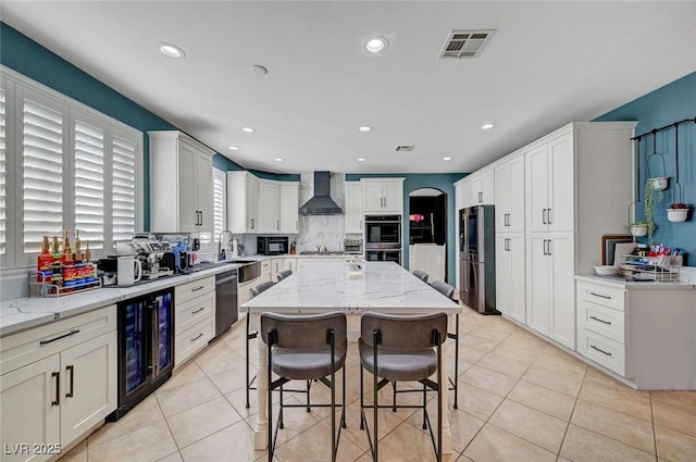 11417 Rock Cove Way, Las Vegas, NV 89141 - kitchen with wall chimney range hood, beverage cooler, appliances with stainless steel finishes, recessed lighting, and light stone countertops