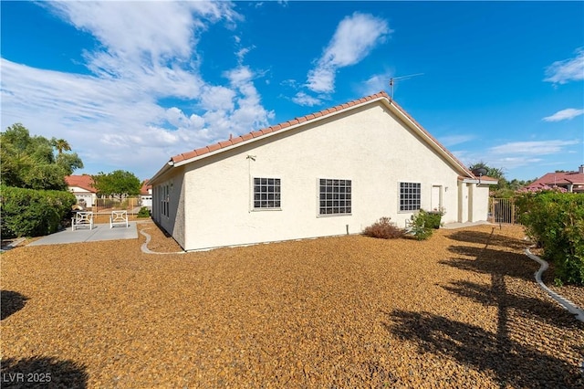 5600 Segolilly Cir, Las Vegas, NV 89130 - view of side of home featuring a patio, a tiled roof, and stucco siding