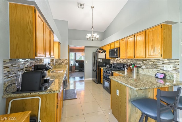 5600 Segolilly Cir, Las Vegas, NV 89130 - kitchen featuring range with two ovens, stainless steel microwave, a peninsula, vaulted ceiling, and light stone counters