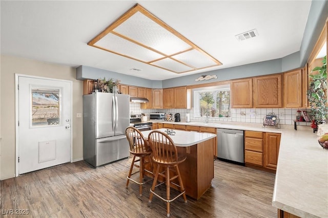 3951 W Blosser Ranch Rd, Pahrump, NV 89060 - kitchen featuring appliances with stainless steel finishes, under cabinet range hood, light countertops, decorative backsplash, and a kitchen breakfast bar