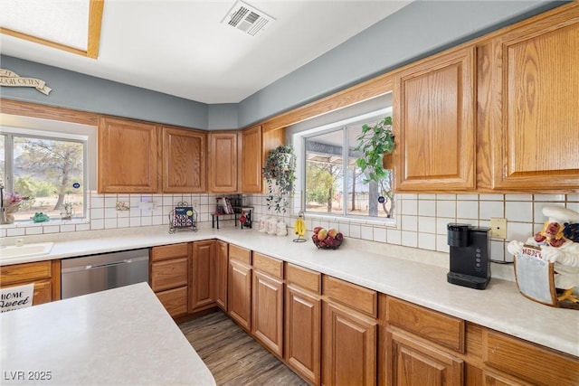 3951 W Blosser Ranch Rd, Pahrump, NV 89060 - kitchen with stainless steel dishwasher, light countertops, tasteful backsplash, light wood-style flooring, and brown cabinets