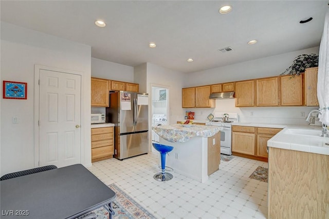 7427 Wagonwheel Ranch Way, Las Vegas, NV 89113 - kitchen featuring white appliances, under cabinet range hood, washer / clothes dryer, a center island, and light countertops