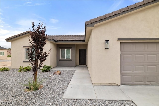 2120 Upland Ave, Pahrump, NV 89048 - view of exterior entry with stucco siding, a garage, and a tile roof
