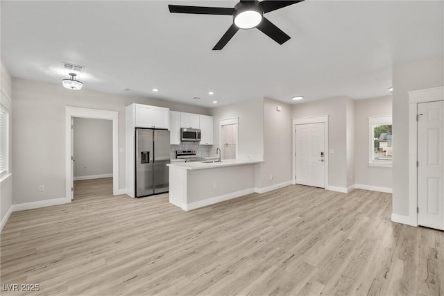 2120 Upland Ave, Pahrump, NV 89048 - kitchen featuring appliances with stainless steel finishes, a peninsula, white cabinets, light countertops, and light wood-type flooring