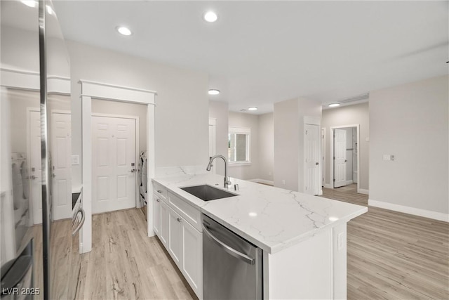 2120 Upland Ave, Pahrump, NV 89048 - kitchen with stainless steel dishwasher, white cabinets, light wood-style flooring, light stone counters, and a peninsula
