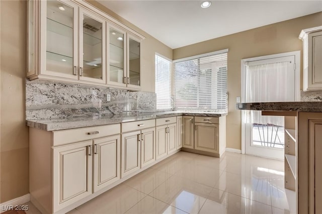 2245 Juniper Berry Dr, Las Vegas, NV 89134 - kitchen with glass insert cabinets, backsplash, light tile patterned flooring, cream cabinetry, and recessed lighting