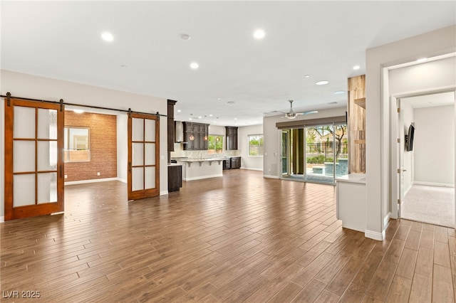 2116 Canvas Edge Dr, Henderson, NV 89044 - unfurnished living room featuring a barn door, recessed lighting, ceiling fan, and dark wood-style flooring