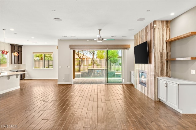 2116 Canvas Edge Dr, Henderson, NV 89044 - unfurnished living room with ceiling fan, a tiled fireplace, wood finished floors, and recessed lighting