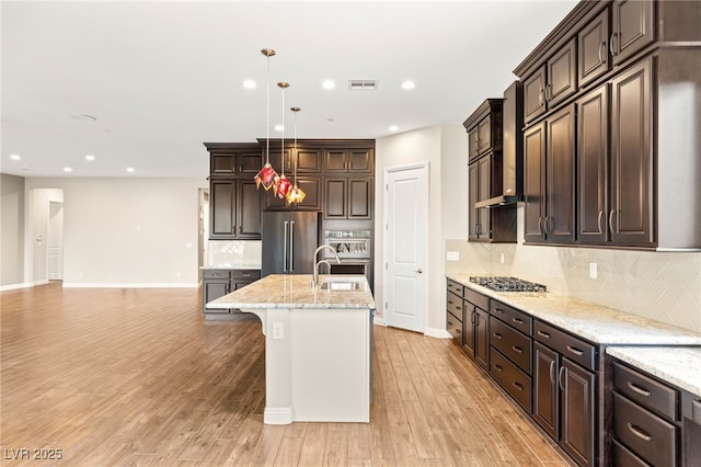 2116 Canvas Edge Dr, Henderson, NV 89044 - kitchen featuring appliances with stainless steel finishes, dark brown cabinets, light wood-type flooring, and recessed lighting