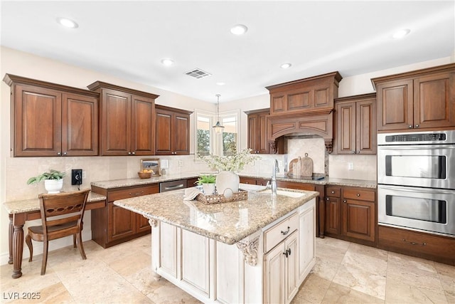 2477 Adobe Wells Dr, Logandale, NV 89021 - kitchen with appliances with stainless steel finishes, an island with sink, decorative backsplash, recessed lighting, and light stone countertops