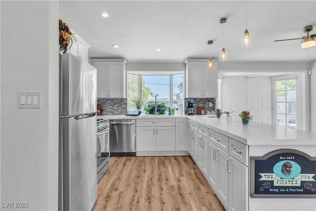 4654 Gabriel Dr, Las Vegas, NV 89121 - kitchen featuring appliances with stainless steel finishes, a peninsula, decorative backsplash, light countertops, and recessed lighting