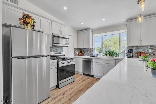 4654 Gabriel Dr, Las Vegas, NV 89121 - kitchen with appliances with stainless steel finishes, backsplash, light stone counters, recessed lighting, and light wood-style flooring