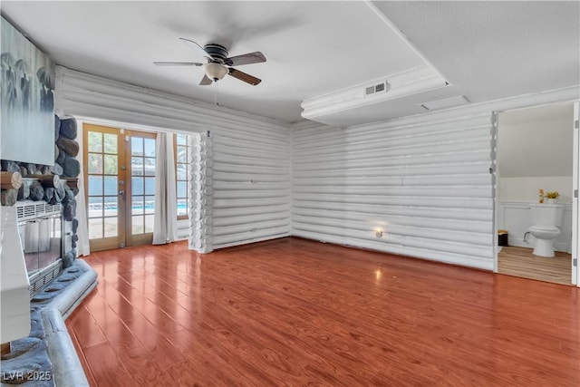 4654 Gabriel Dr, Las Vegas, NV 89121 - unfurnished living room featuring wood finished floors, a ceiling fan, french doors, rustic walls, and a stone fireplace