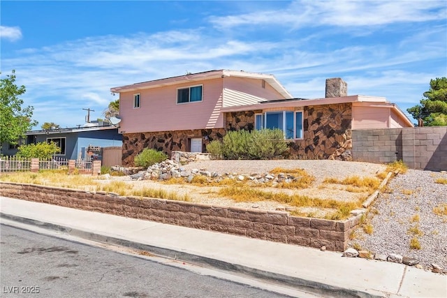 4654 Gabriel Dr, Las Vegas, NV 89121 - tri-level home featuring stone siding and a chimney