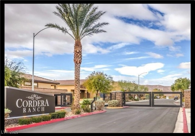 1860 Moonbow Falls St, Henderson, NV 89044 - view of asphalt road featuring a gate, curbs, street lighting, a gated entry, and a mountain view