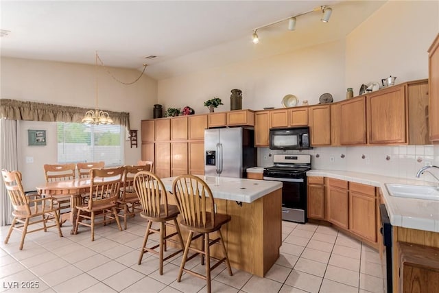 8840 Spinning Wheel Ave, Las Vegas, NV 89143 - kitchen featuring appliances with stainless steel finishes, tile countertops, light tile patterned flooring, a center island, and a chandelier