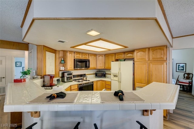 1939 Guinn Dr, Henderson, NV 89074 - kitchen with white appliances, tile counters, a peninsula, light wood-style flooring, and a textured ceiling