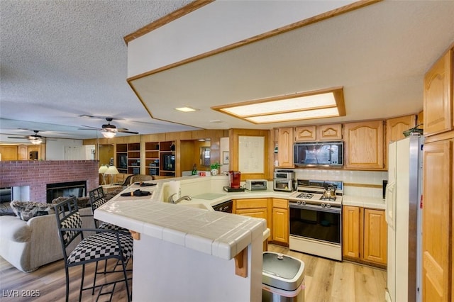 1939 Guinn Dr, Henderson, NV 89074 - kitchen featuring white appliances, a peninsula, tile counters, open floor plan, and a breakfast bar