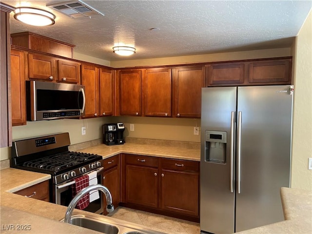 6868 Sky Pointe Dr Unit 1132, Las Vegas, NV 89131 - kitchen featuring stainless steel appliances, light countertops, a textured ceiling, and brown cabinetry