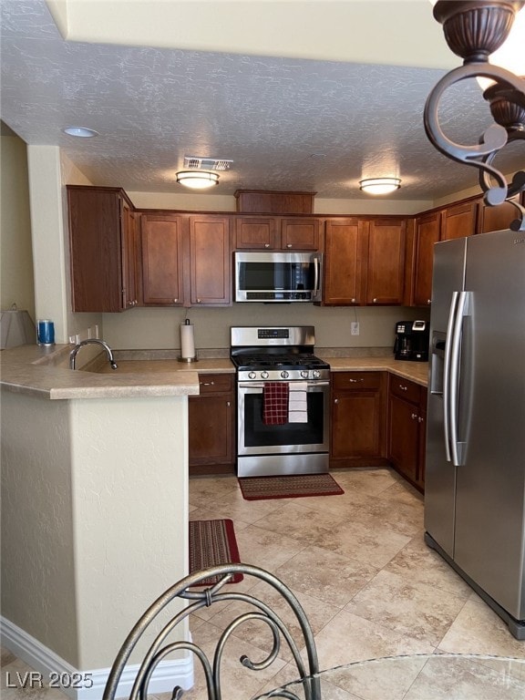 6868 Sky Pointe Dr Unit 1132, Las Vegas, NV 89131 - kitchen featuring stainless steel appliances, light countertops, a textured ceiling, a peninsula, and brown cabinetry