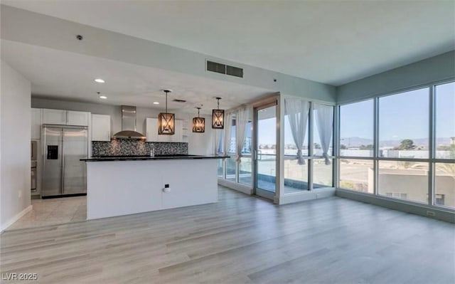 4575 Dean Martin Dr Unit 406, Las Vegas, NV 89103 - kitchen with stainless steel built in fridge, wall chimney range hood, dark countertops, white cabinetry, and light wood finished floors