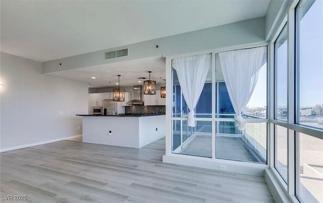 4575 Dean Martin Dr Unit 406, Las Vegas, NV 89103 - kitchen featuring healthy amount of natural light, wall chimney exhaust hood, dark countertops, and a chandelier