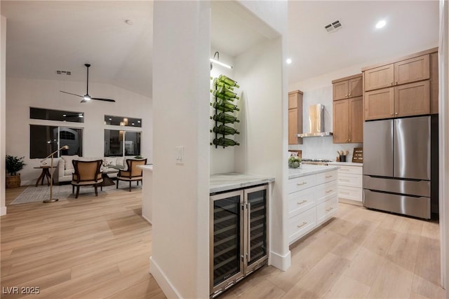 4065 Genoa Dr, Las Vegas, NV 89141 - kitchen with appliances with stainless steel finishes, wine cooler, wall chimney range hood, light wood-style flooring, and a ceiling fan