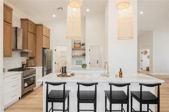 4065 Genoa Dr, Las Vegas, NV 89141 - kitchen featuring wall chimney exhaust hood, stainless steel appliances, open shelves, tasteful backsplash, and a kitchen bar