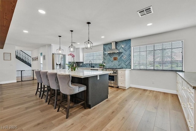 2740 Family Ct, Las Vegas, NV 89117 - kitchen featuring stainless steel appliances, wall chimney range hood, white cabinetry, tasteful backsplash, and recessed lighting