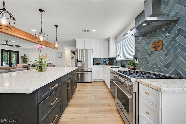 2740 Family Ct, Las Vegas, NV 89117 - kitchen featuring stainless steel appliances, wall chimney range hood, plenty of natural light, white cabinetry, and recessed lighting