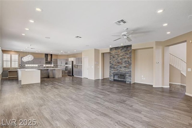8113 Gothic Ave, Las Vegas, NV 89117 - unfurnished living room featuring dark wood-style flooring, a ceiling fan, recessed lighting, a fireplace, and stairway