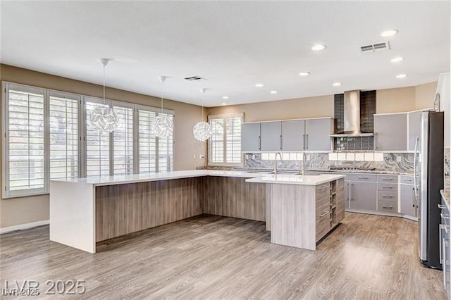 8113 Gothic Ave, Las Vegas, NV 89117 - kitchen with wall chimney range hood, light wood finished floors, decorative backsplash, light countertops, and recessed lighting