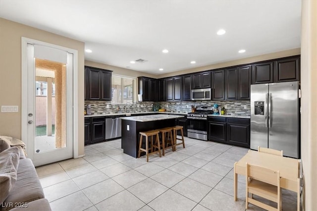 6301 Beavertail Pond Ave, Las Vegas, NV 89122 - kitchen featuring stainless steel appliances, open floor plan, a breakfast bar, decorative backsplash, and a kitchen island
