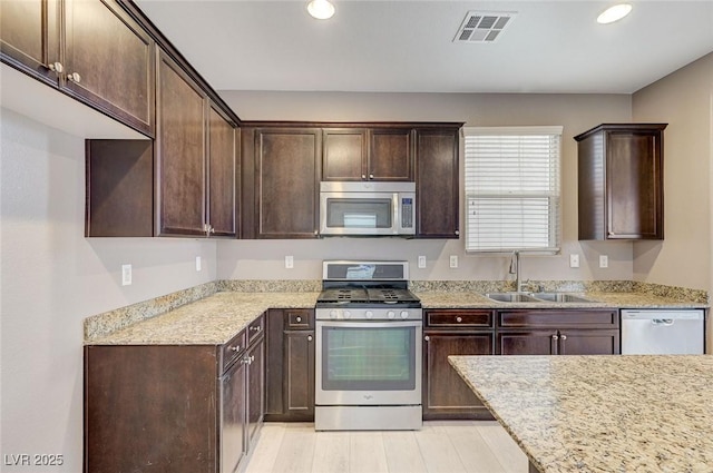 7534 Earnshaw Ave, Las Vegas, NV 89179 - kitchen with appliances with stainless steel finishes, dark brown cabinets, recessed lighting, light stone counters, and light wood finished floors