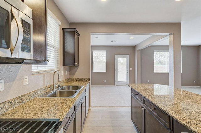 7534 Earnshaw Ave, Las Vegas, NV 89179 - kitchen with stainless steel microwave, dark brown cabinetry, light stone counters, light wood-type flooring, and recessed lighting