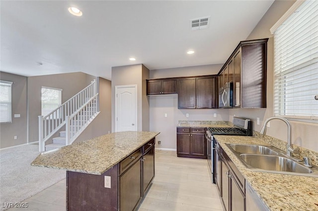 7534 Earnshaw Ave, Las Vegas, NV 89179 - kitchen with appliances with stainless steel finishes, dark brown cabinetry, a center island, light stone countertops, and recessed lighting