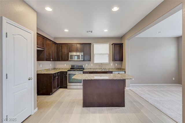 7534 Earnshaw Ave, Las Vegas, NV 89179 - kitchen featuring appliances with stainless steel finishes, a kitchen island, dark brown cabinetry, light stone countertops, and recessed lighting