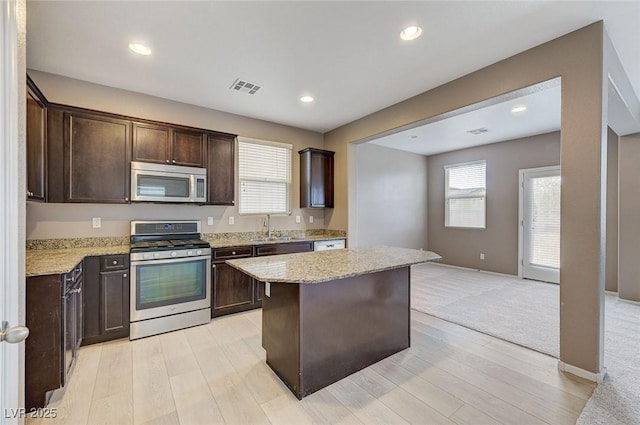 7534 Earnshaw Ave, Las Vegas, NV 89179 - kitchen with stainless steel appliances, dark brown cabinets, light stone countertops, a kitchen island, and recessed lighting